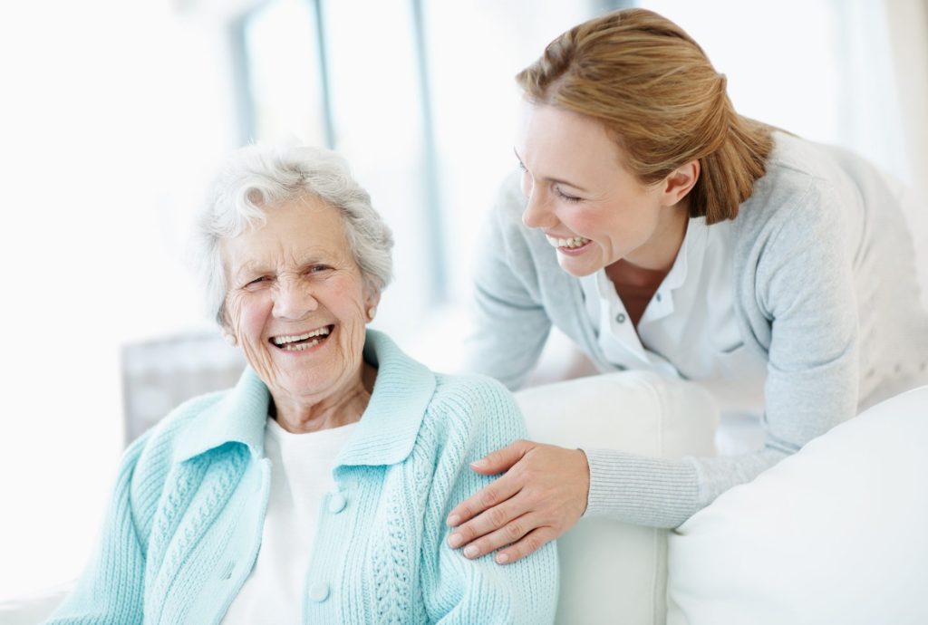 Elderly woman and caretaker share a laugh